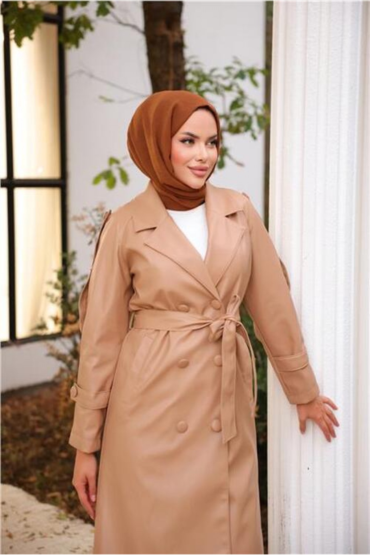 Double-breasted, pocketed, drawstring waist leather trench coat.