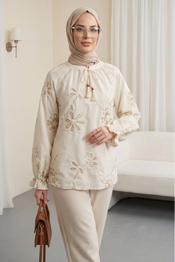 Long-sleeved blouse with tassel detail and floral embroidery. -Cream color